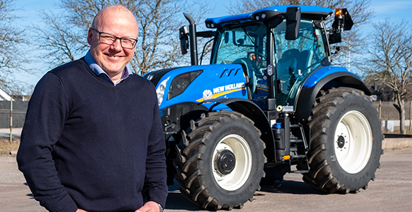 man står framför blå traktor