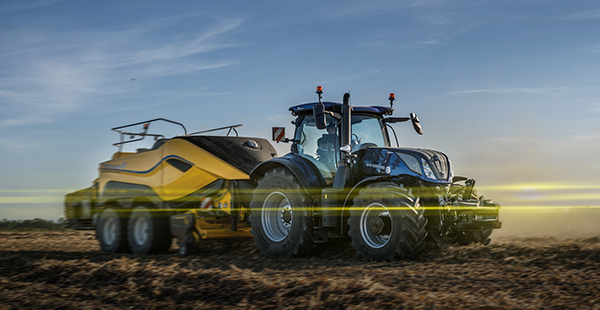 blå traktor med gult släp på fält med blå himmel