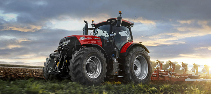 Röd traktor med plog på fält